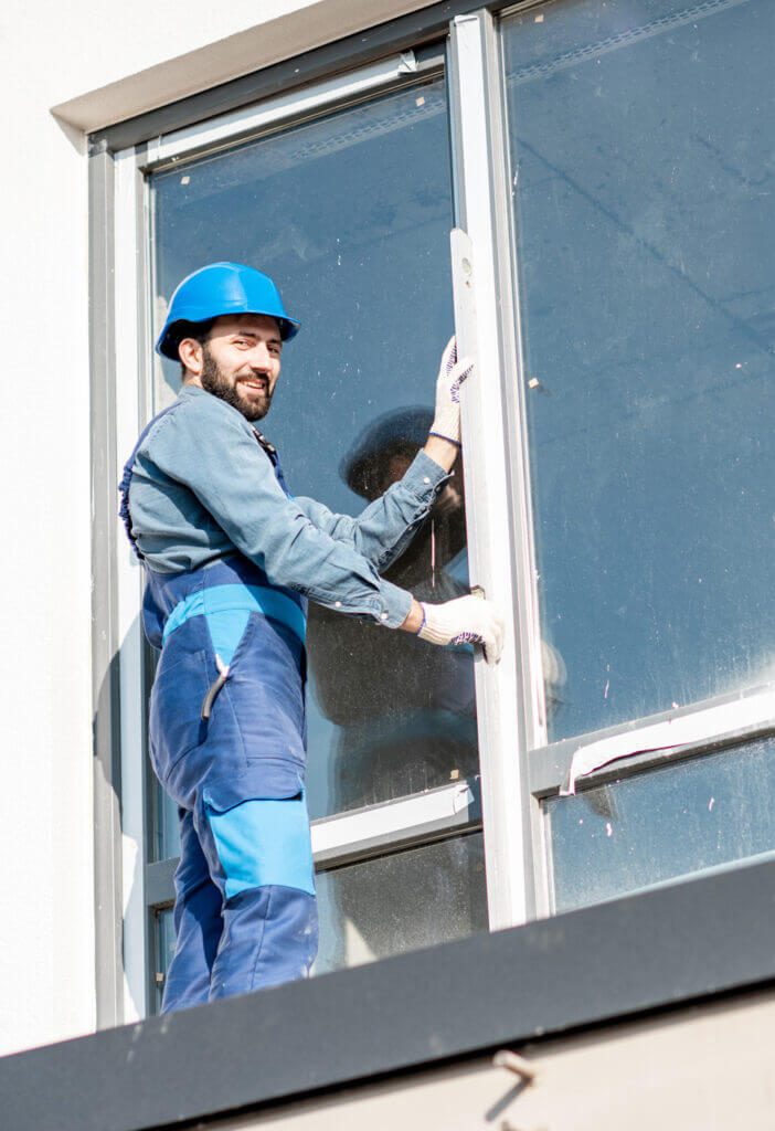 dělník stojící na parapetu při výměně okna